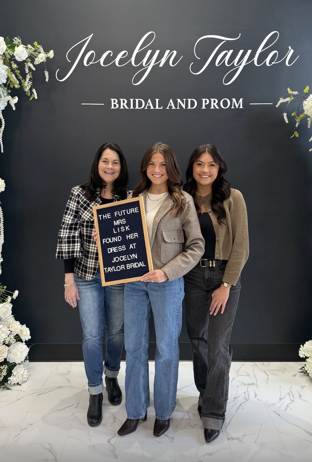Bride and guests holding up sign saying "The Future Mrs. Lisk found her dress at Jocelyn Taylor Bridal"